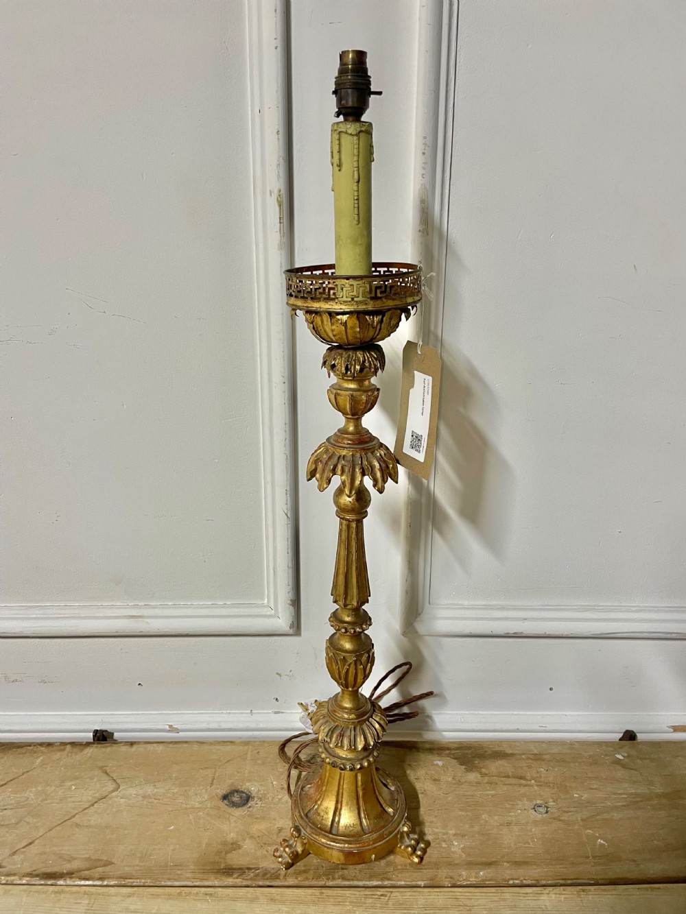 A tall Italian giltwood table lamp styled as a candlestick with acanthus leaf carvings, a fluted stem, and a faux candle sleeve.
