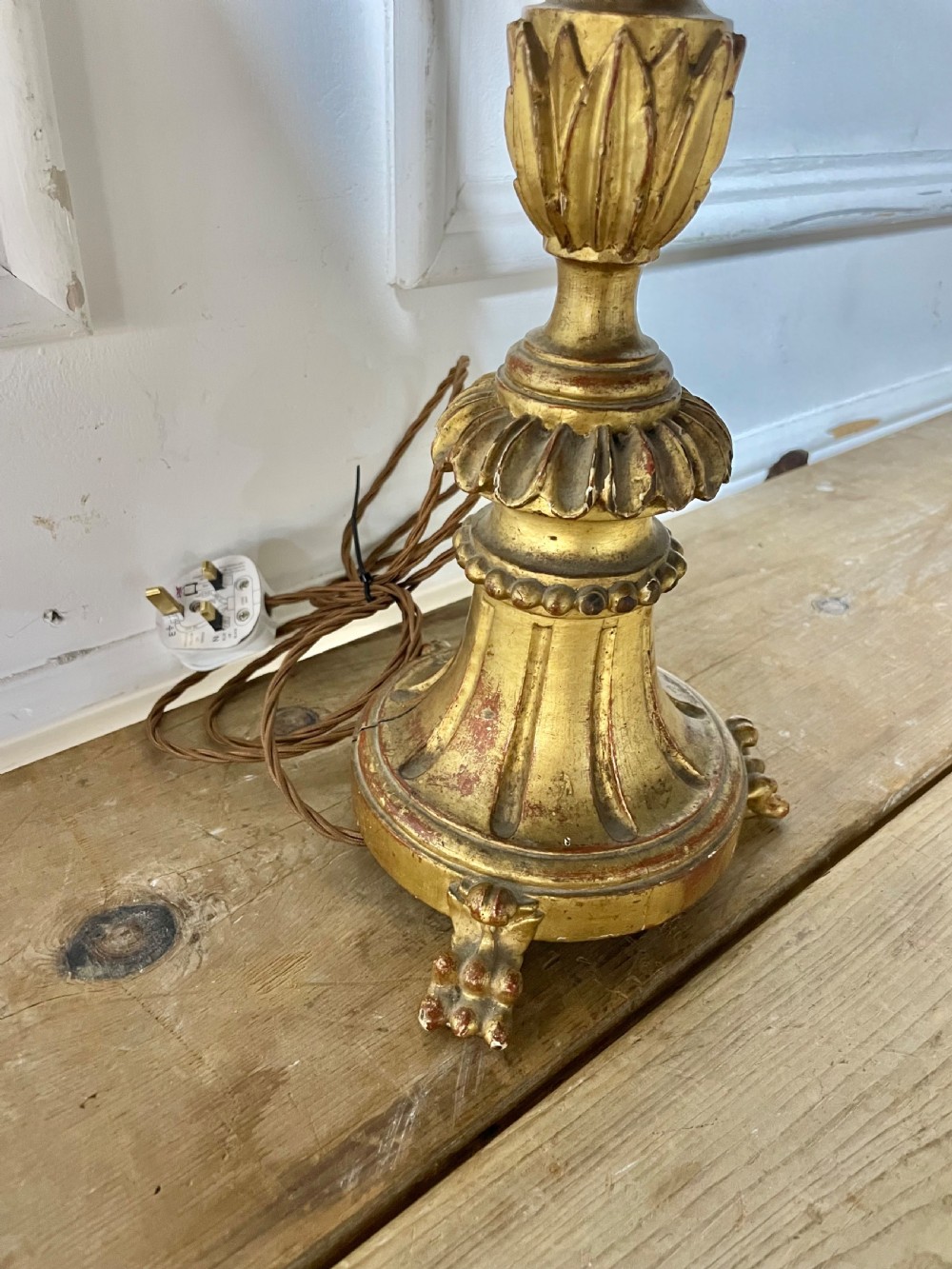 A tall Italian giltwood table lamp styled as a candlestick with acanthus leaf carvings, a fluted stem, and a faux candle sleeve. View VII