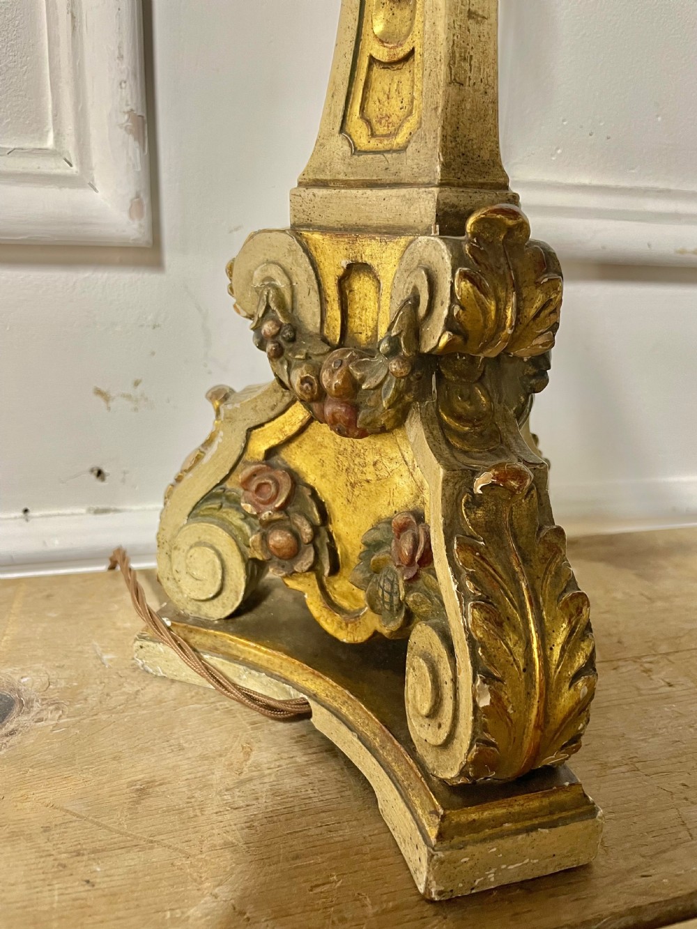 A tall, carved giltwood and cream painted table lamp base featuring neoclassical scrollwork and floral swags. View V