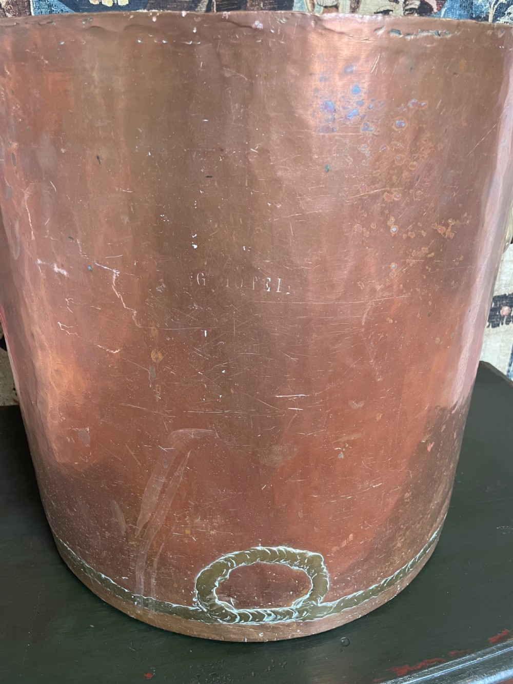 A large cylindrical copper log bin featuring two cast brass side handles and a hammered metal finish. View VII