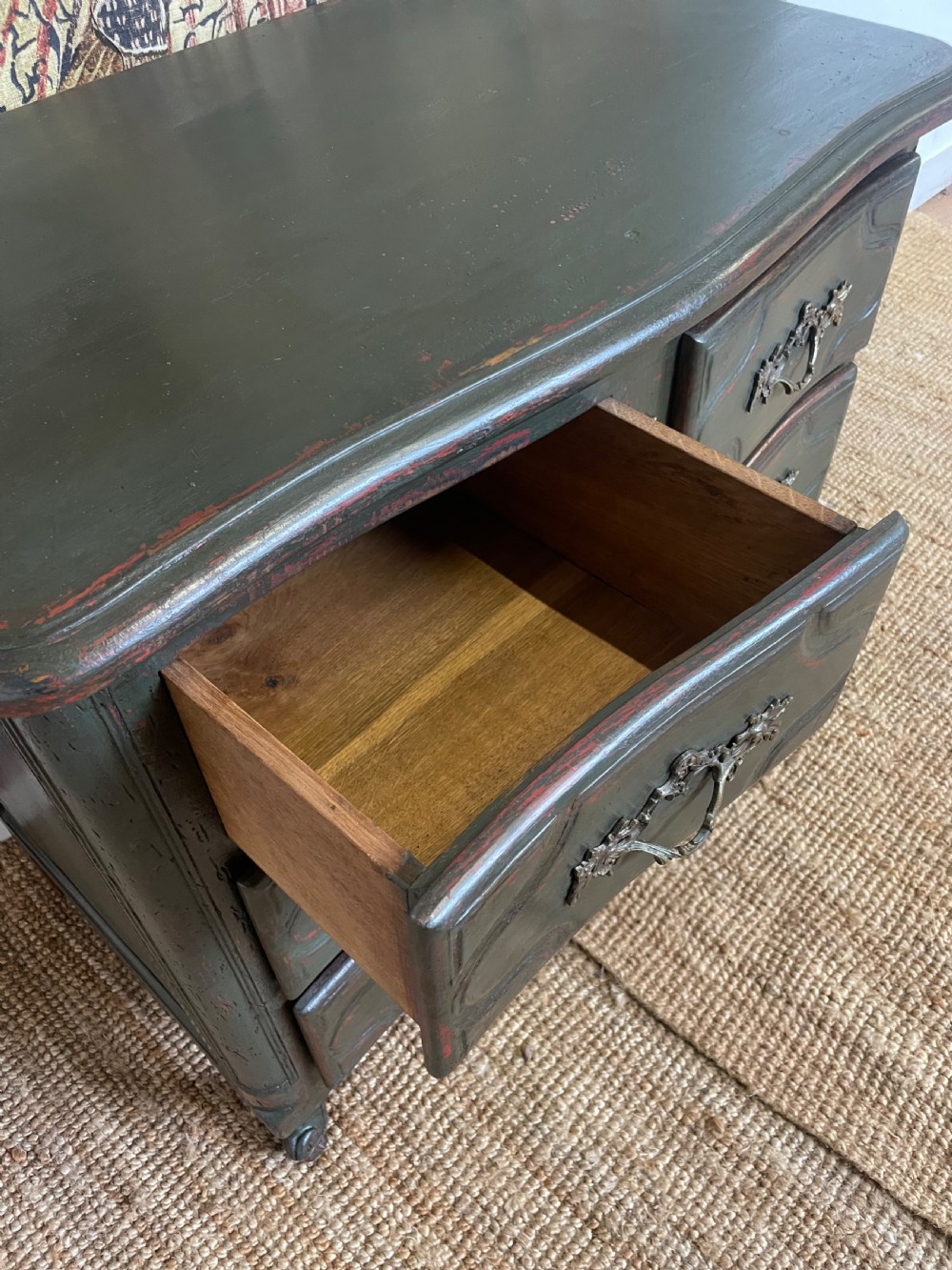 A dark green painted French commode chest of drawers featuring moulded panels, distressed finish, and decorative brass handles. View V