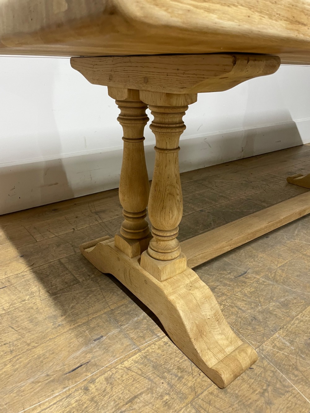 A long rectangular scrubbed oak refectory table featuring turned pedestal supports and a central stretcher. View X