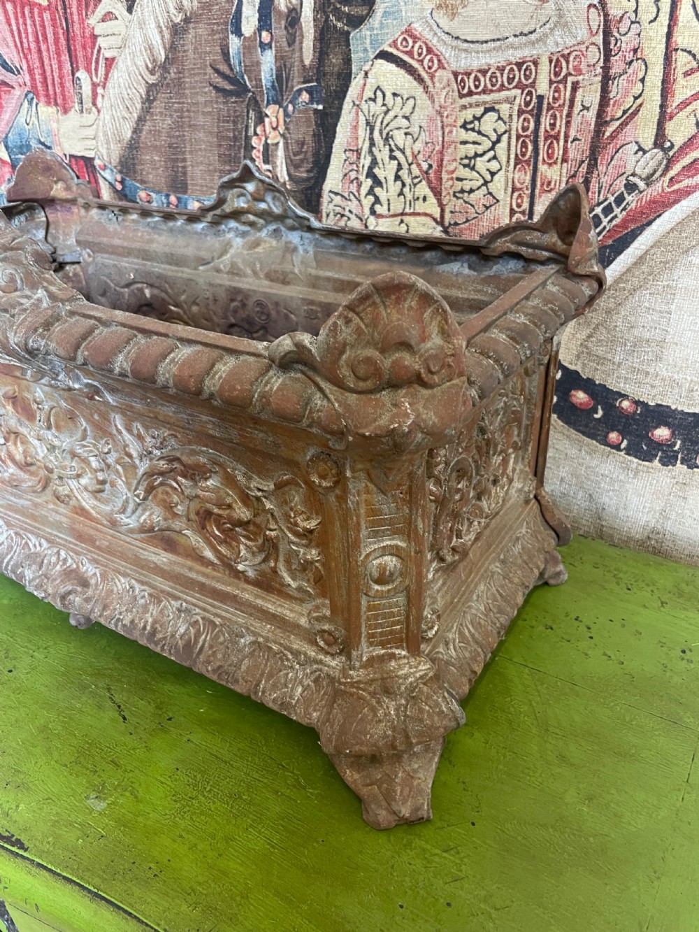 A rectangular cast iron planter trough featuring ornate relief scrollwork, foliate motifs, and a weathered rust patina. View II