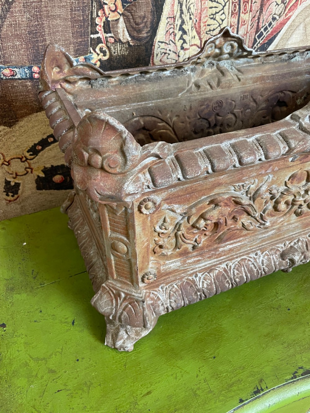 A rectangular cast iron planter trough featuring ornate relief scrollwork, foliate motifs, and a weathered rust patina. View VII