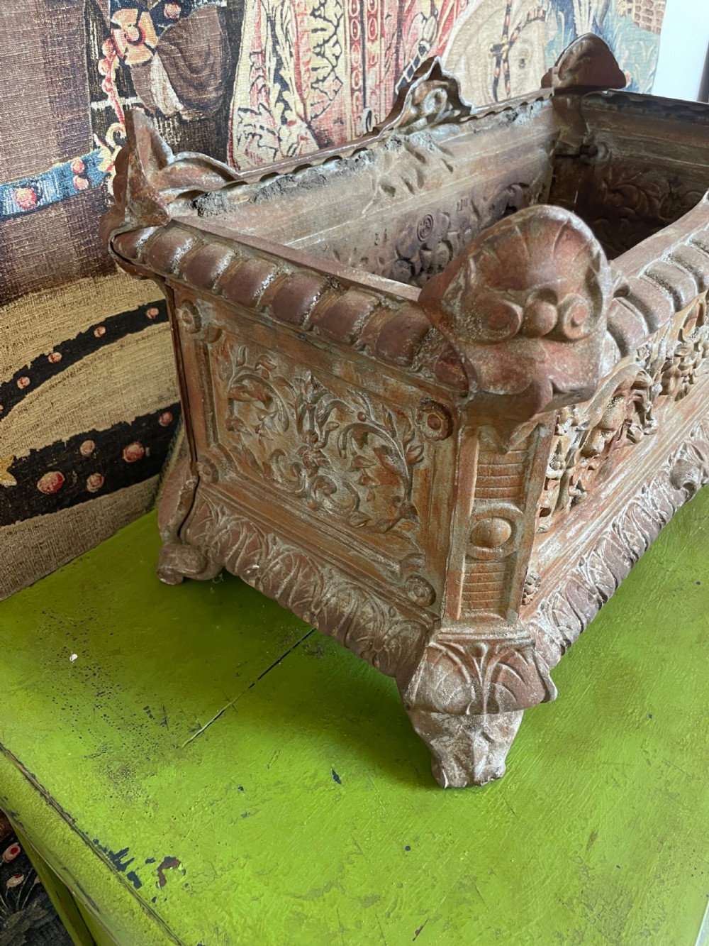 A rectangular cast iron planter trough featuring ornate relief scrollwork, foliate motifs, and a weathered rust patina. View VIII