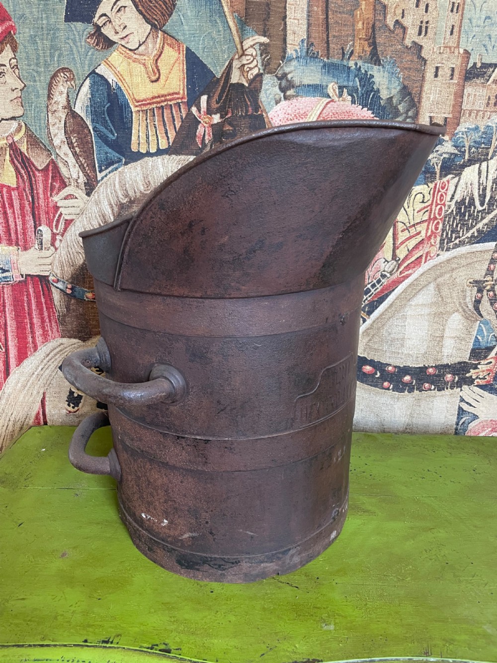 A heavy dark iron industrial measure vessel featuring double side handles, a contoured upper spout, and a patinated metal surface.