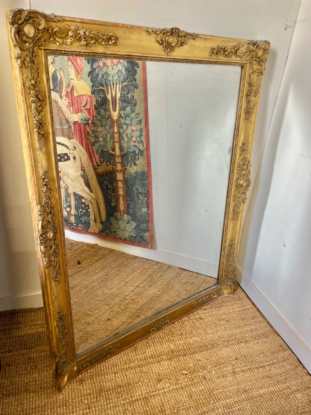 A large early 19th-century rectangular overmantle mirror with a detailed gold leaf frame featuring carved acanthus motifs and a central crest.