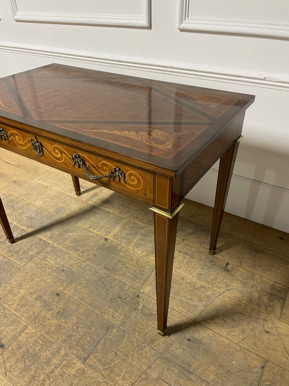 A rectangular antique wooden writing table featuring intricate geometric and floral marquetry on the top and frieze drawer, accented with cast brass mounts and tapering legs. View II