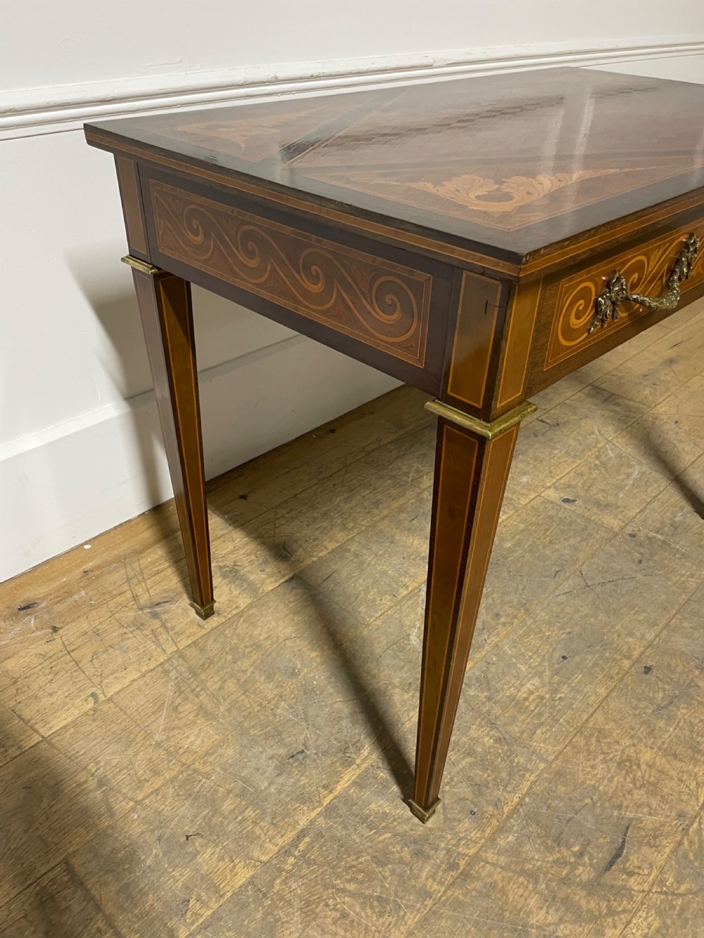 A rectangular antique wooden writing table featuring intricate geometric and floral marquetry on the top and frieze drawer, accented with cast brass mounts and tapering legs. View IV
