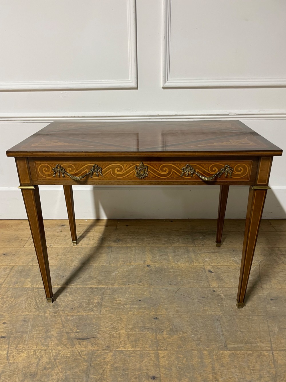 A rectangular antique wooden writing table featuring intricate geometric and floral marquetry on the top and frieze drawer, accented with cast brass mounts and tapering legs. View VI