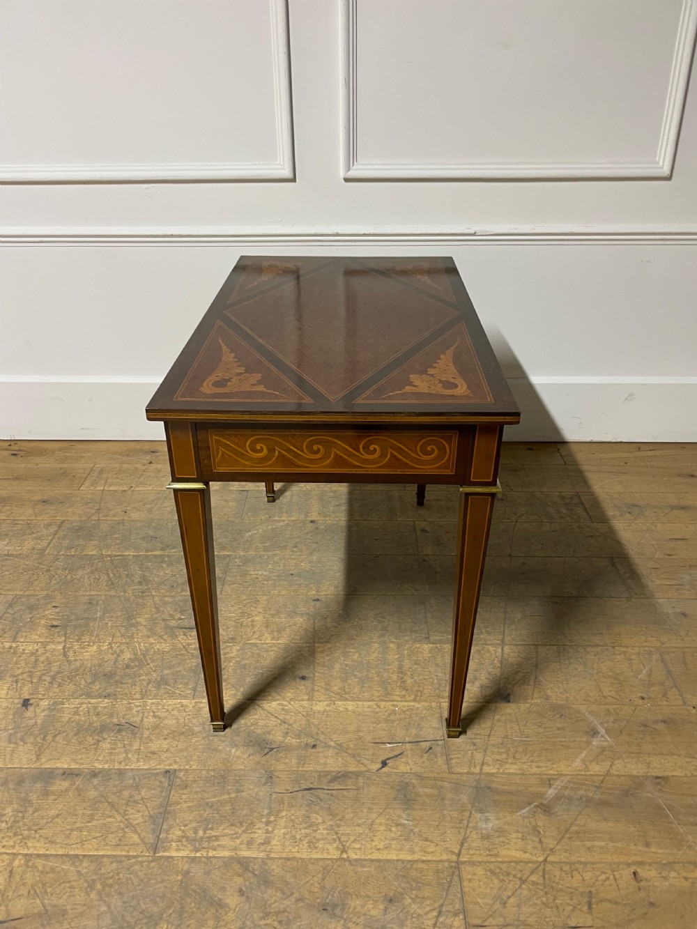A rectangular antique wooden writing table featuring intricate geometric and floral marquetry on the top and frieze drawer, accented with cast brass mounts and tapering legs. View VII