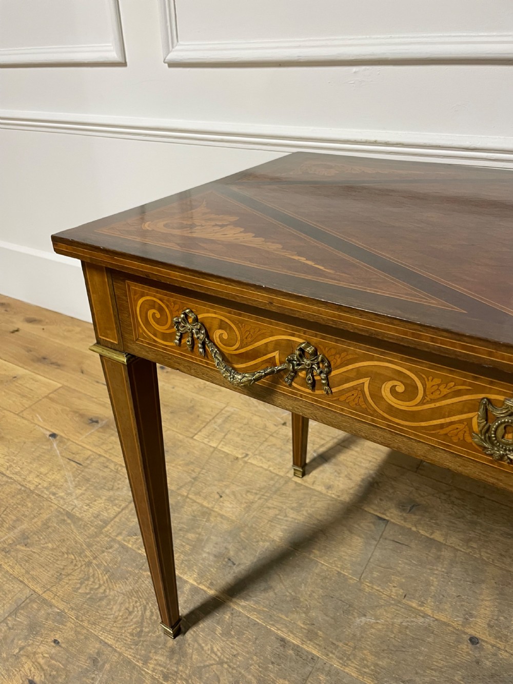 A rectangular antique wooden writing table featuring intricate geometric and floral marquetry on the top and frieze drawer, accented with cast brass mounts and tapering legs. View VIII