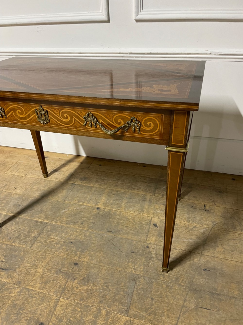 A rectangular antique wooden writing table featuring intricate geometric and floral marquetry on the top and frieze drawer, accented with cast brass mounts and tapering legs. View X