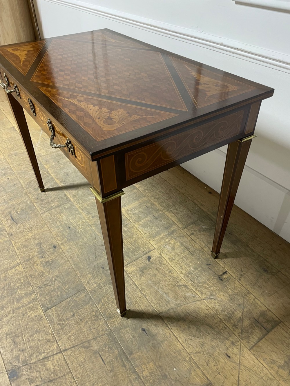 A rectangular antique wooden writing table featuring intricate geometric and floral marquetry on the top and frieze drawer, accented with cast brass mounts and tapering legs. View XI