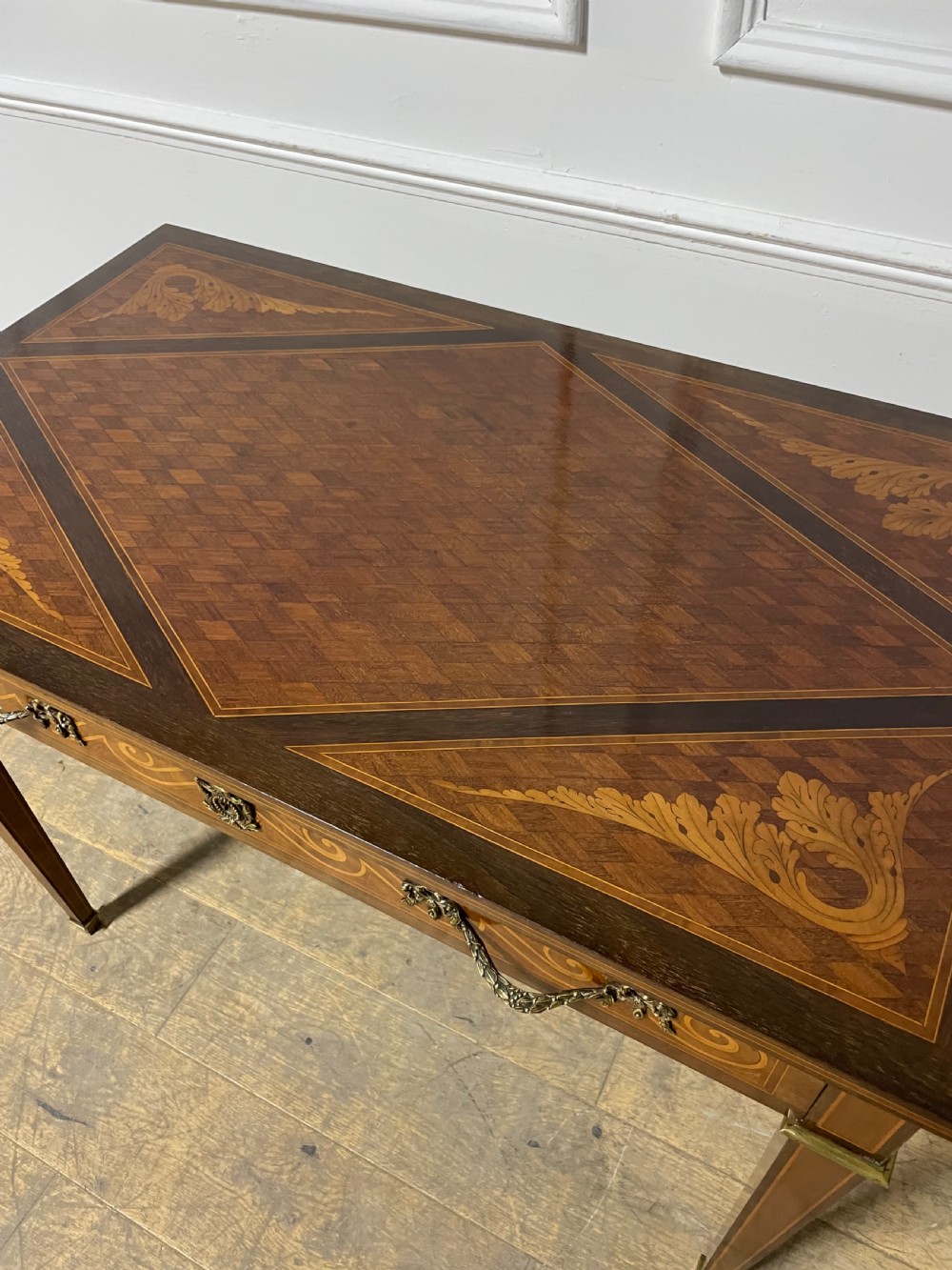A rectangular antique wooden writing table featuring intricate geometric and floral marquetry on the top and frieze drawer, accented with cast brass mounts and tapering legs. View XIII