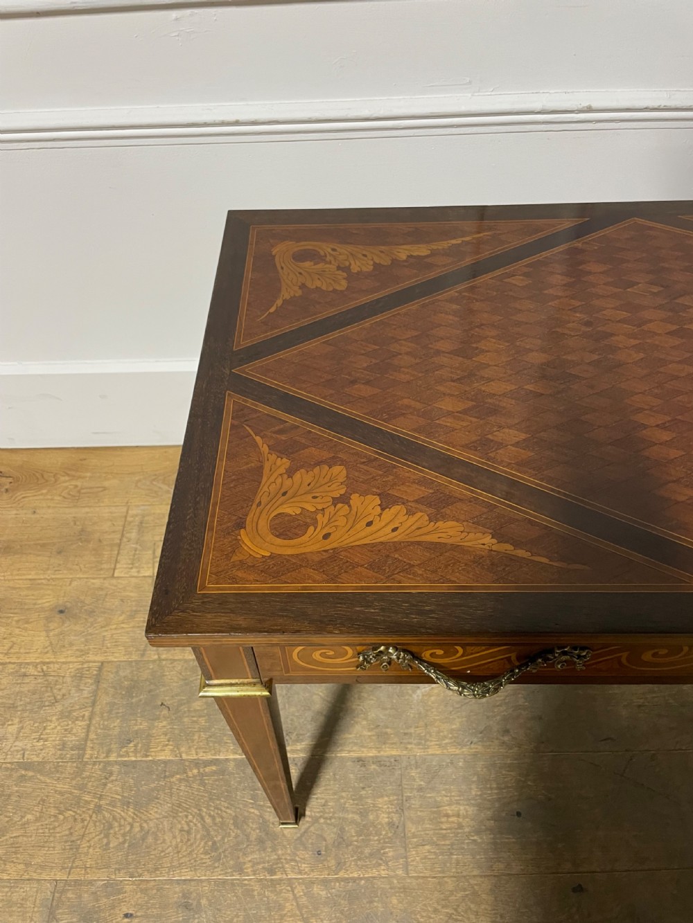 A rectangular antique wooden writing table featuring intricate geometric and floral marquetry on the top and frieze drawer, accented with cast brass mounts and tapering legs. View XV