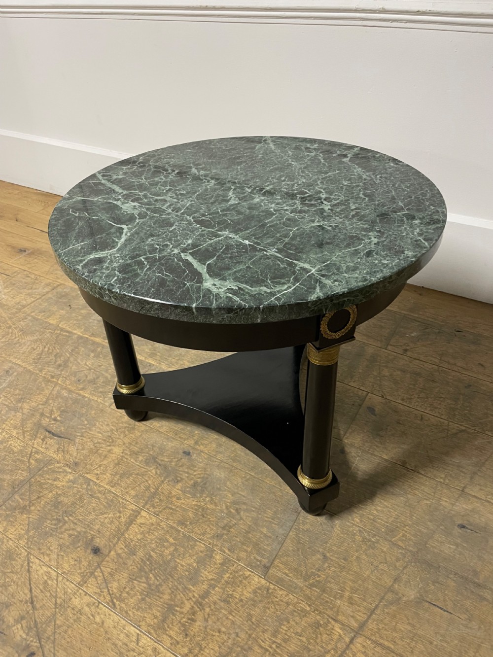 A circular Empire style table featuring a polished green marble top, ebonised column legs with gilt brass mounts, and a concave triform base. View II