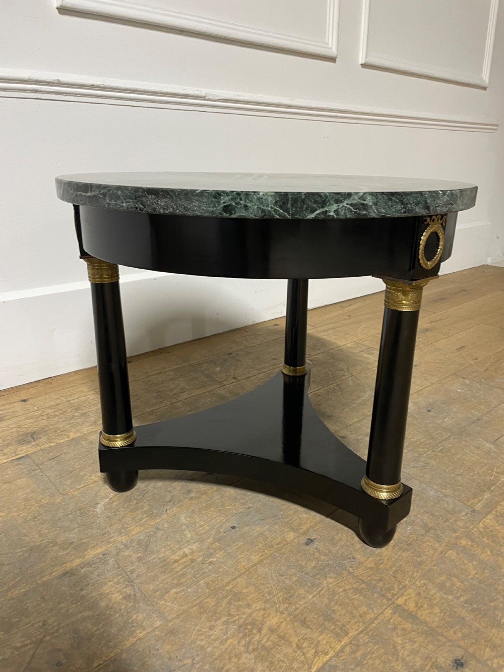 A circular Empire style table featuring a polished green marble top, ebonised column legs with gilt brass mounts, and a concave triform base. View III
