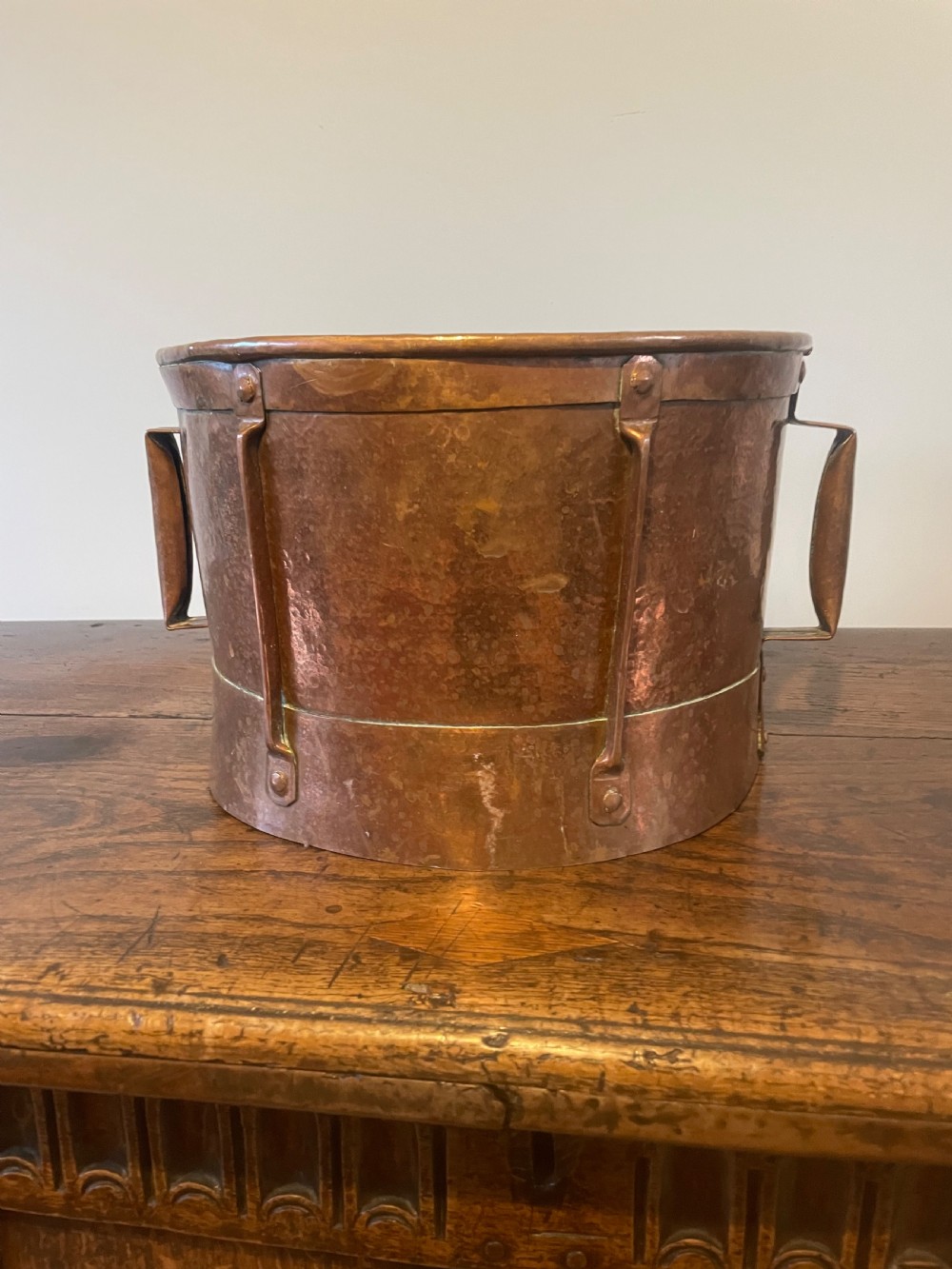 Nineteenth-century hand-hammered copper ferrat bucket featuring riveted vertical support straps and twin side handles.