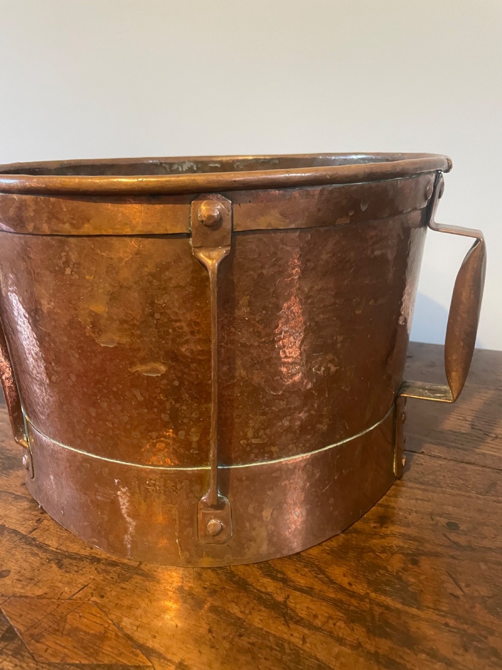 Nineteenth-century hand-hammered copper ferrat bucket featuring riveted vertical support straps and twin side handles. View II