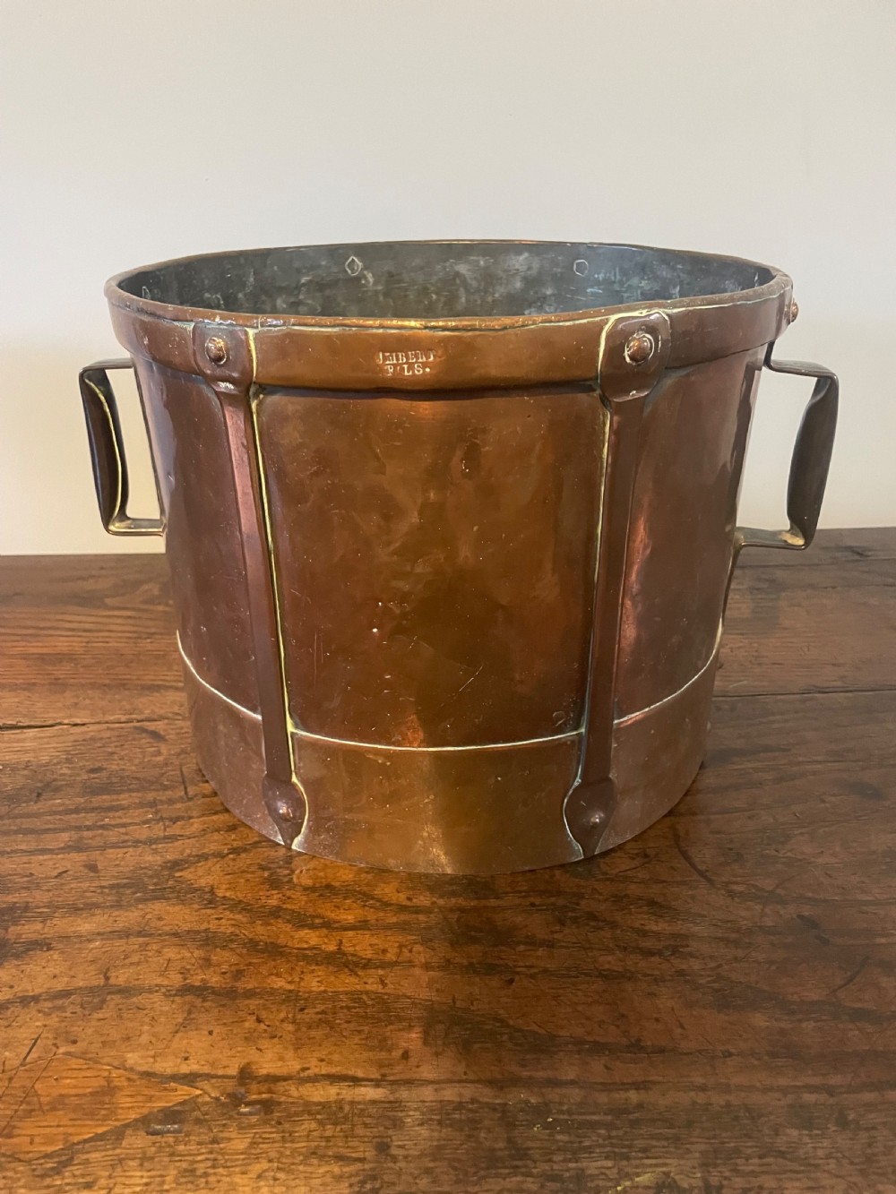 A 19th-century French cylindrical copper bucket featuring riveted vertical reinforcing bands, dual side handles, and a stamped makers mark.