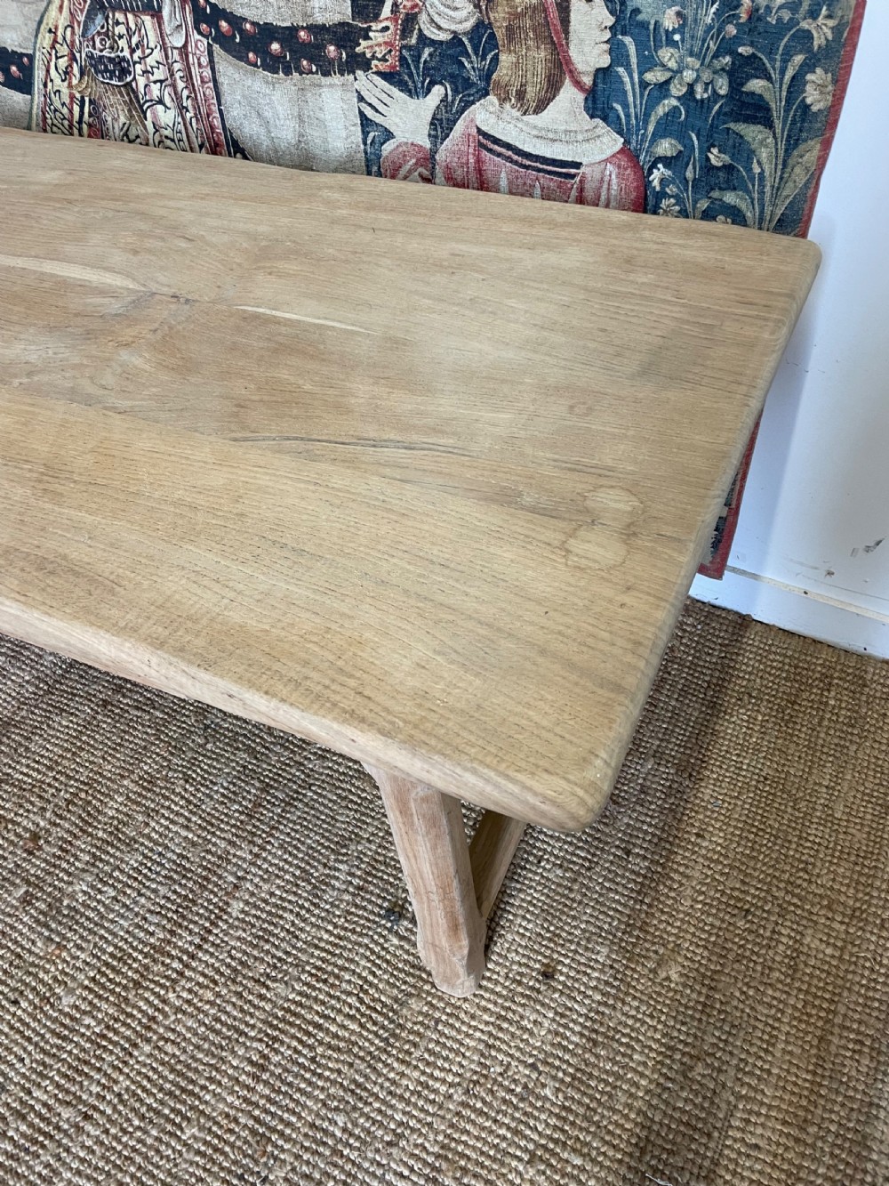 A long light oak farmhouse table featuring a rectangular plank top, two frieze drawers with dark metal handles, and square legs joined by a low stretcher. View III