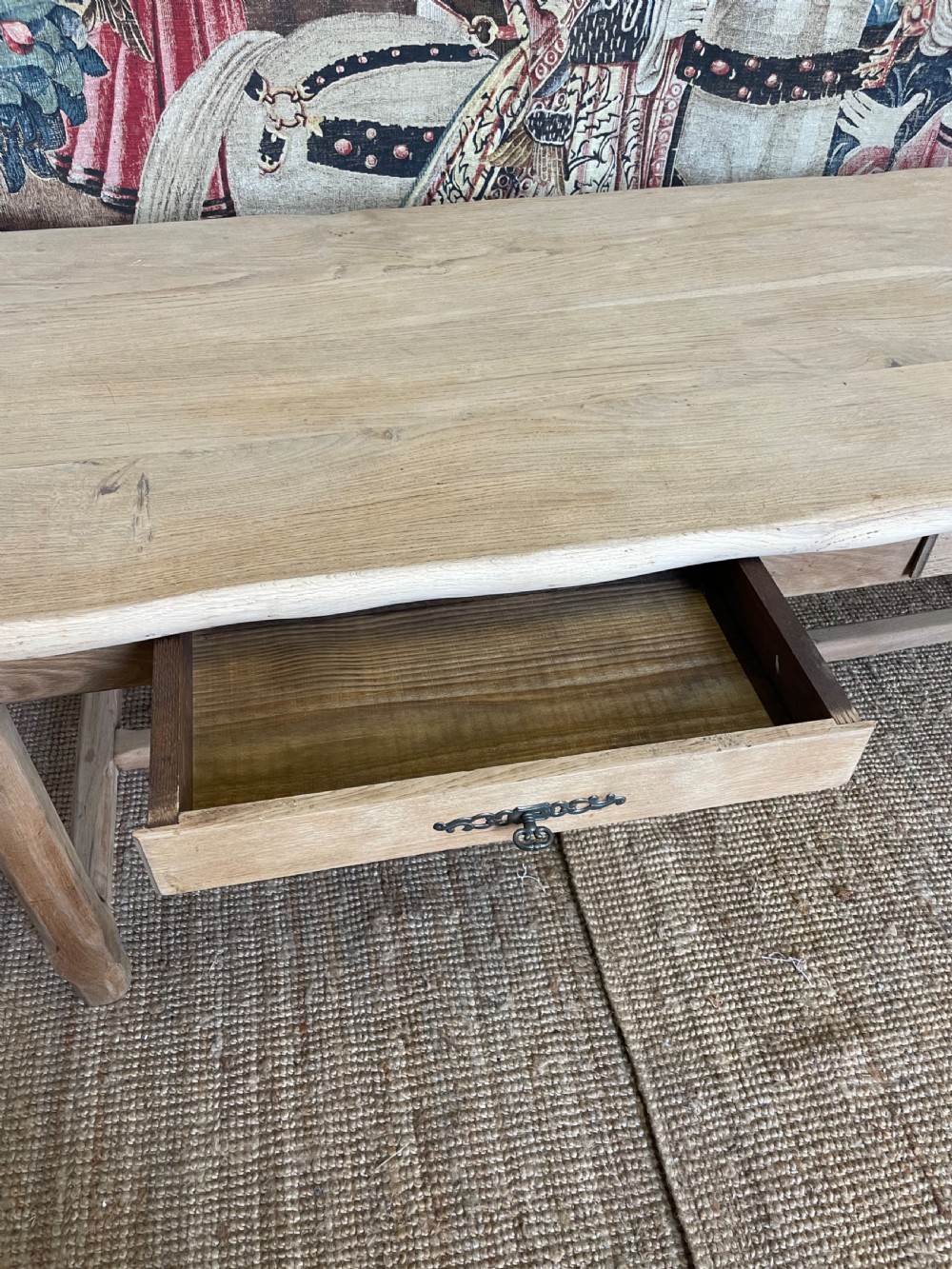 A long light oak farmhouse table featuring a rectangular plank top, two frieze drawers with dark metal handles, and square legs joined by a low stretcher. View IV