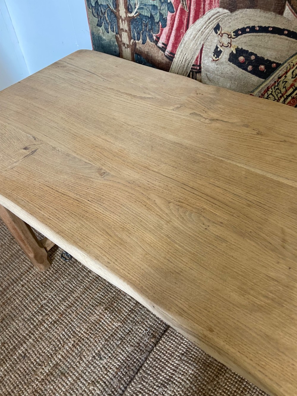 A long light oak farmhouse table featuring a rectangular plank top, two frieze drawers with dark metal handles, and square legs joined by a low stretcher. View V