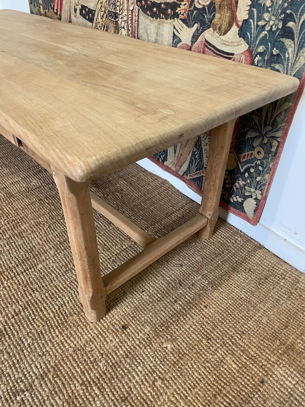 A long light oak farmhouse table featuring a rectangular plank top, two frieze drawers with dark metal handles, and square legs joined by a low stretcher. View IX