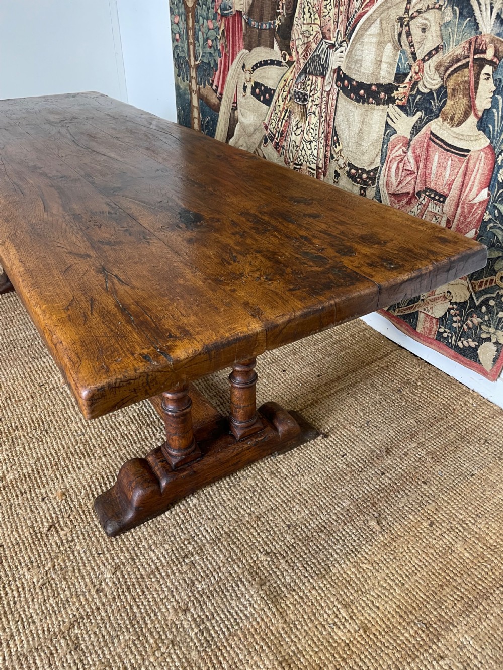 A long rectangular wooden refectory table featuring a plank top and turned leg supports joined by a low stretcher. View III