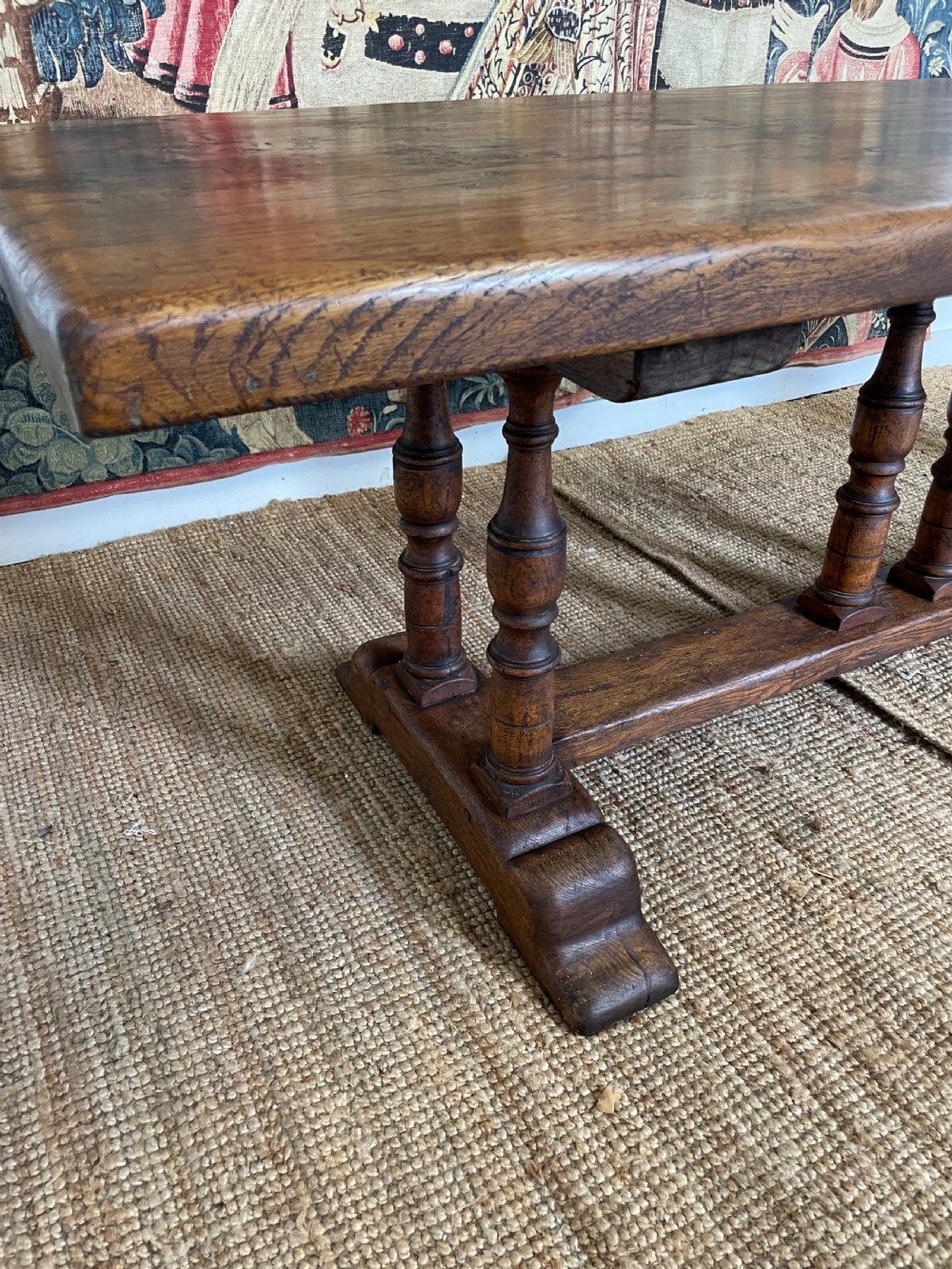 A long rectangular wooden refectory table featuring a plank top and turned leg supports joined by a low stretcher. View X