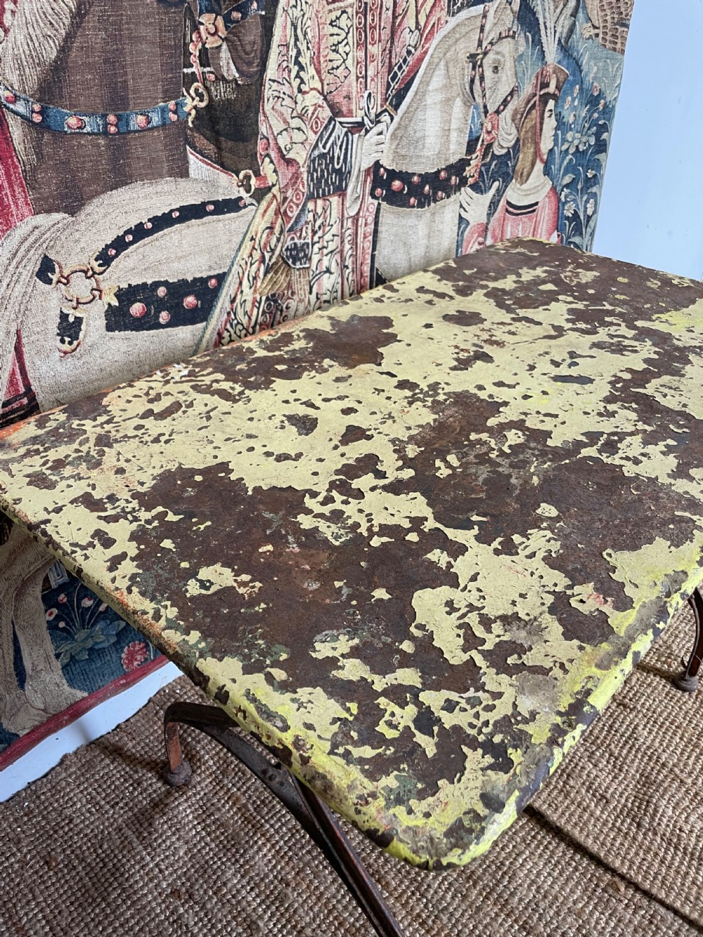 An antique rectangular metal garden table with a distressed yellow painted top and curved iron legs. View IV