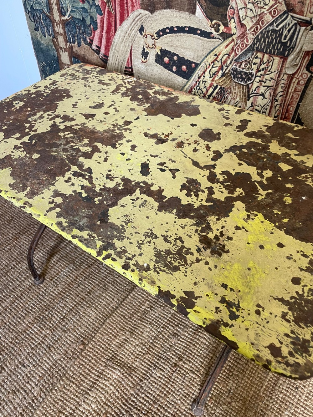 An antique rectangular metal garden table with a distressed yellow painted top and curved iron legs. View V