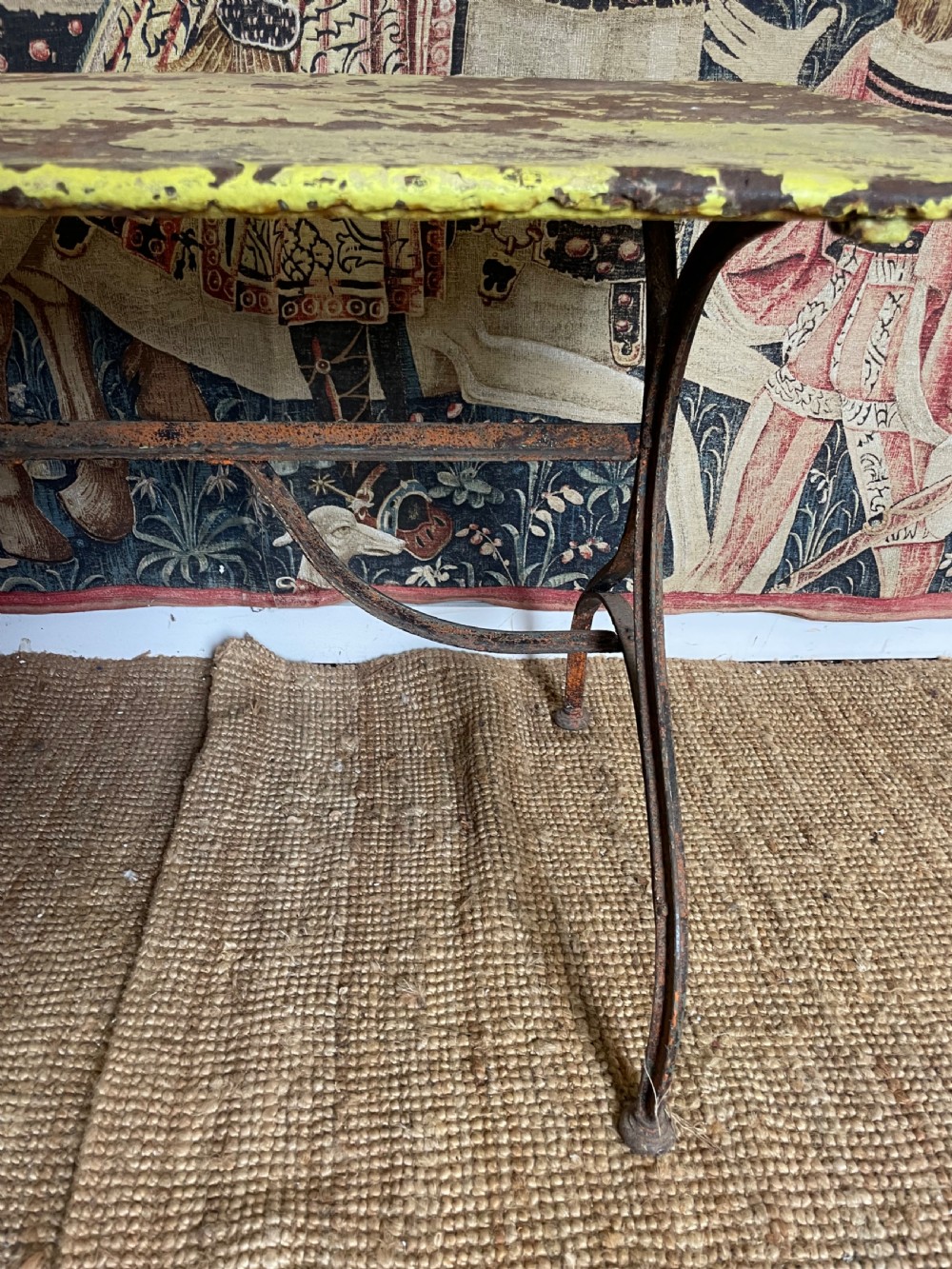 An antique rectangular metal garden table with a distressed yellow painted top and curved iron legs. View VII