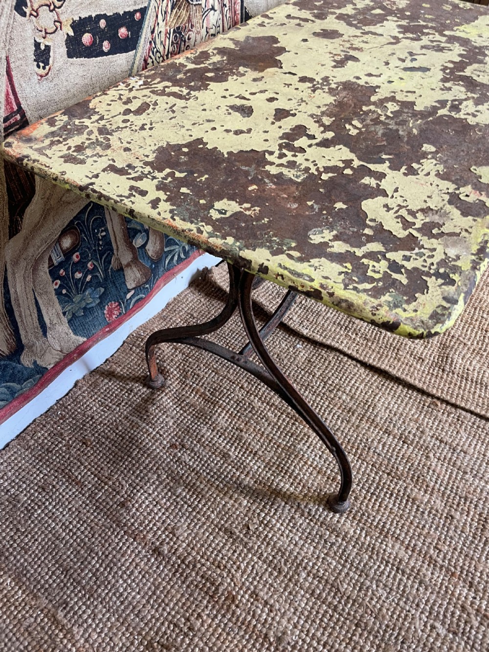 An antique rectangular metal garden table with a distressed yellow painted top and curved iron legs. View IX