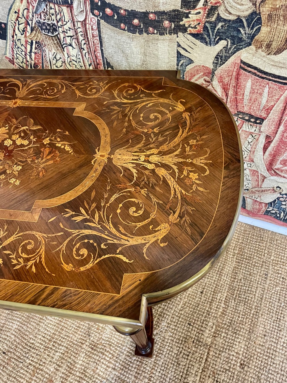 An antique rosewood writing table featuring intricate floral marquetry inlay across the top and stretcher base, complemented by brass edging and turned supports. View IV