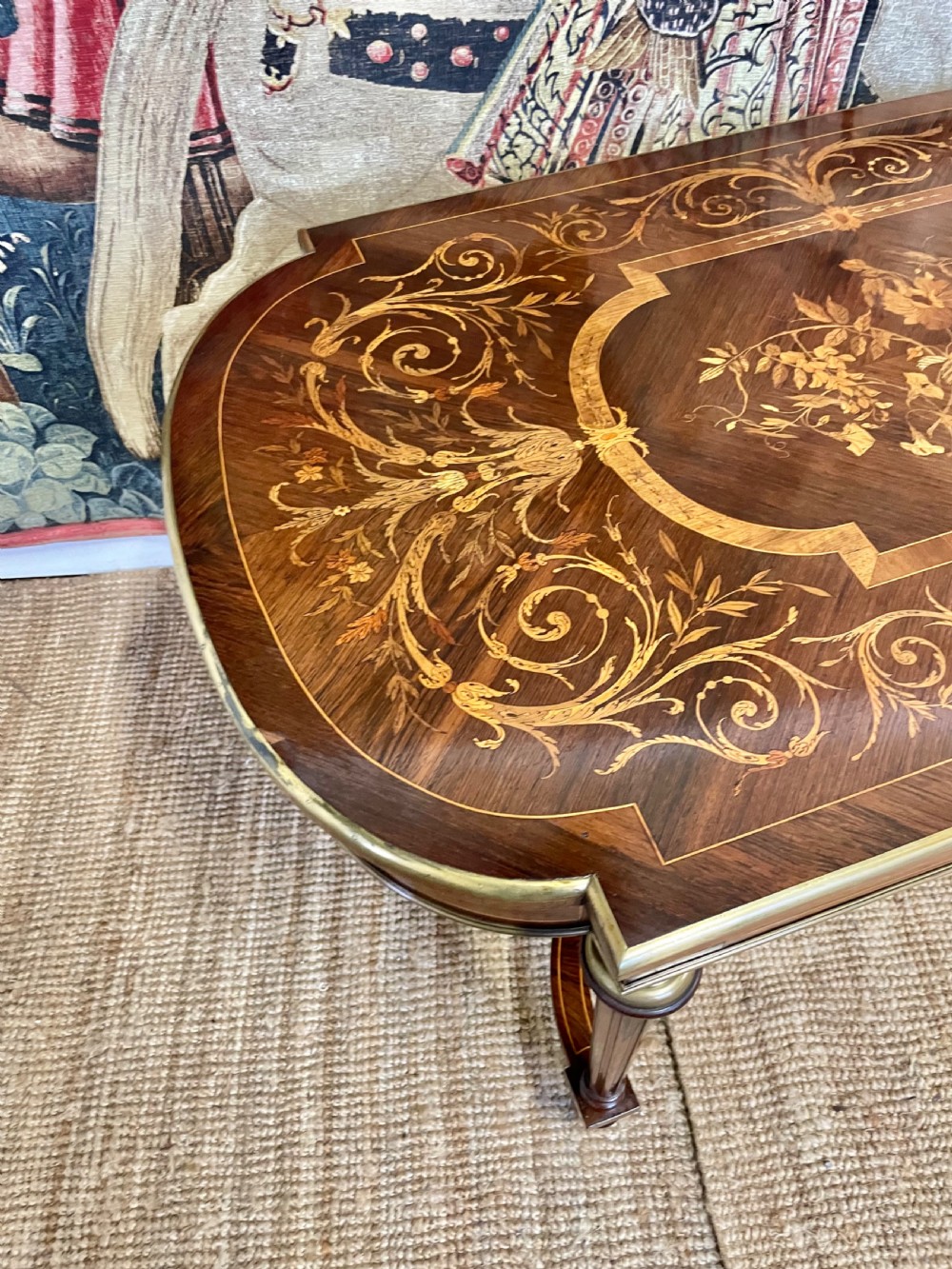 An antique rosewood writing table featuring intricate floral marquetry inlay across the top and stretcher base, complemented by brass edging and turned supports. View VII