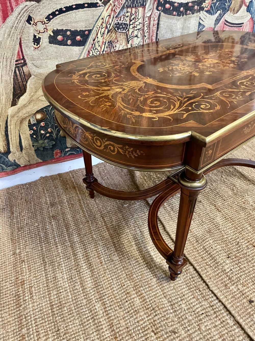 An antique rosewood writing table featuring intricate floral marquetry inlay across the top and stretcher base, complemented by brass edging and turned supports. View VIII