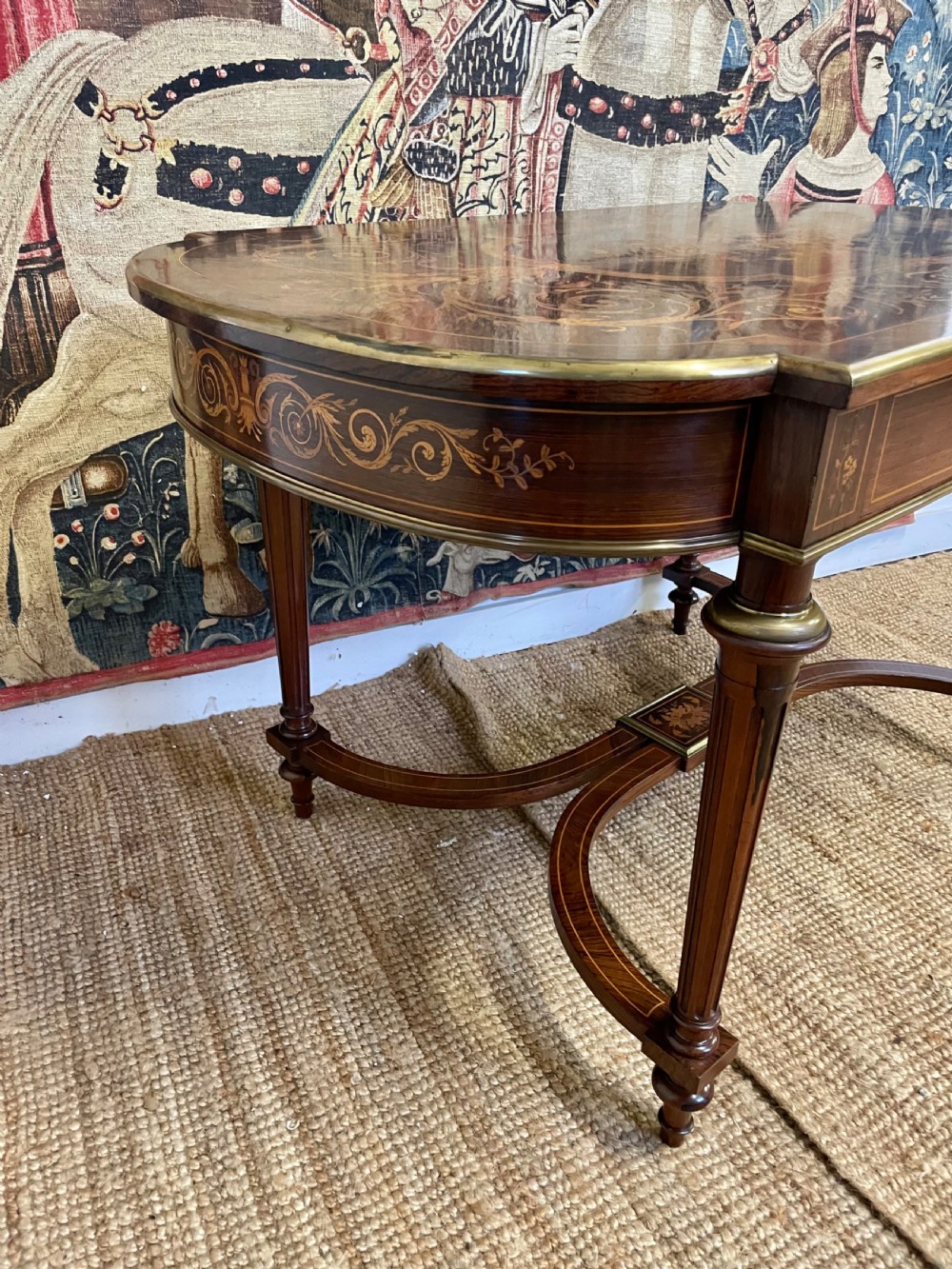 An antique rosewood writing table featuring intricate floral marquetry inlay across the top and stretcher base, complemented by brass edging and turned supports. View IX