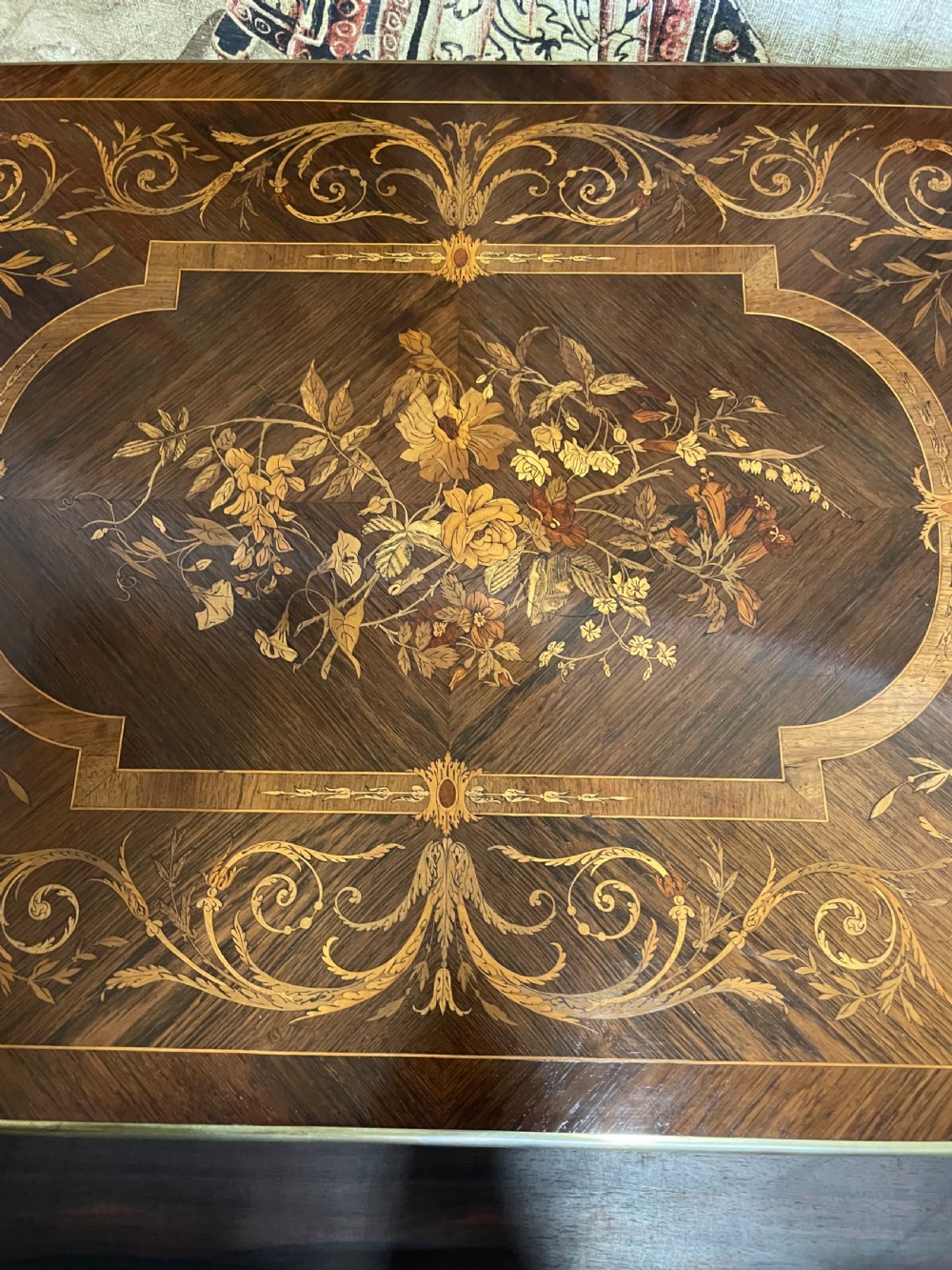 An antique rosewood writing table featuring intricate floral marquetry inlay across the top and stretcher base, complemented by brass edging and turned supports. View XII