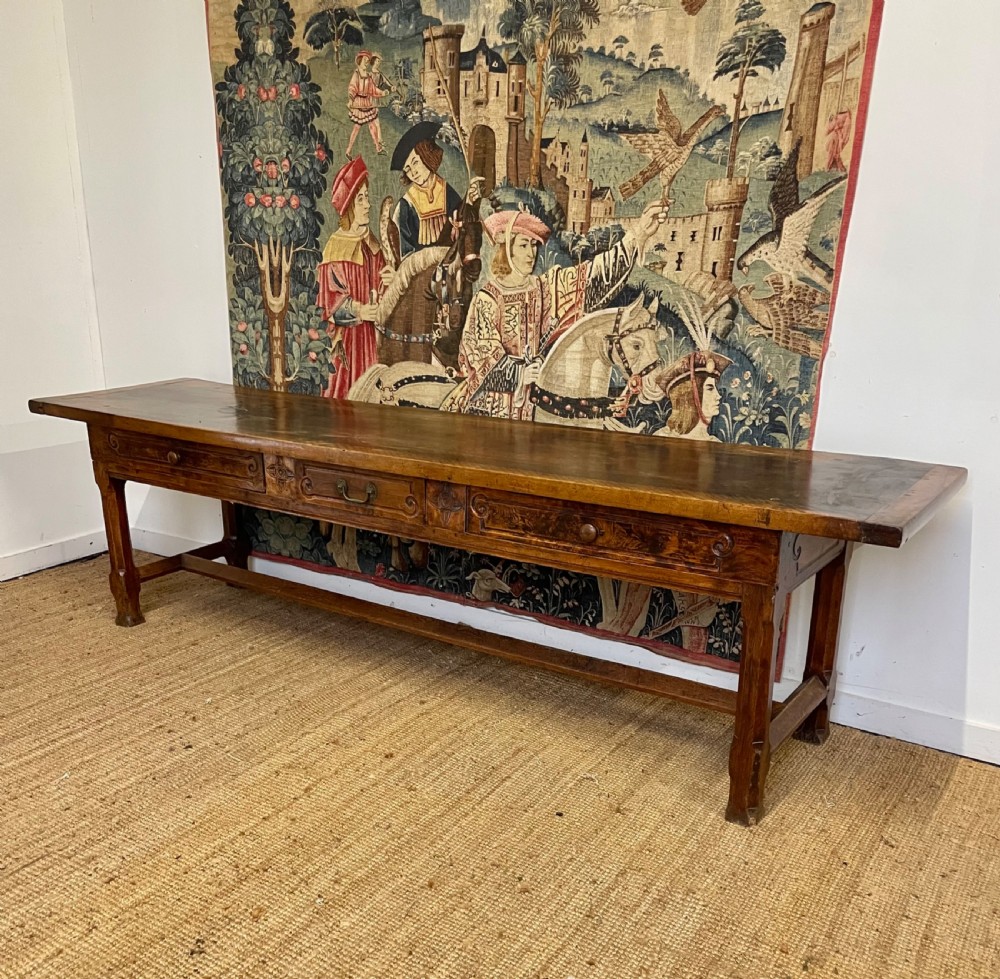 An elongated antique walnut console table featuring three drawers with brass hardware and low stretcher supports. View VI
