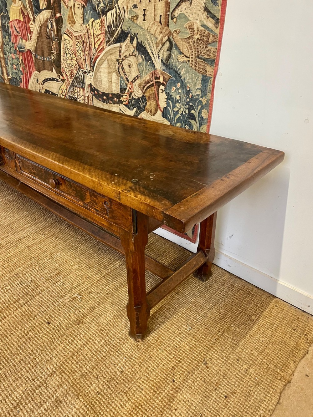 An elongated antique walnut console table featuring three drawers with brass hardware and low stretcher supports. View IX