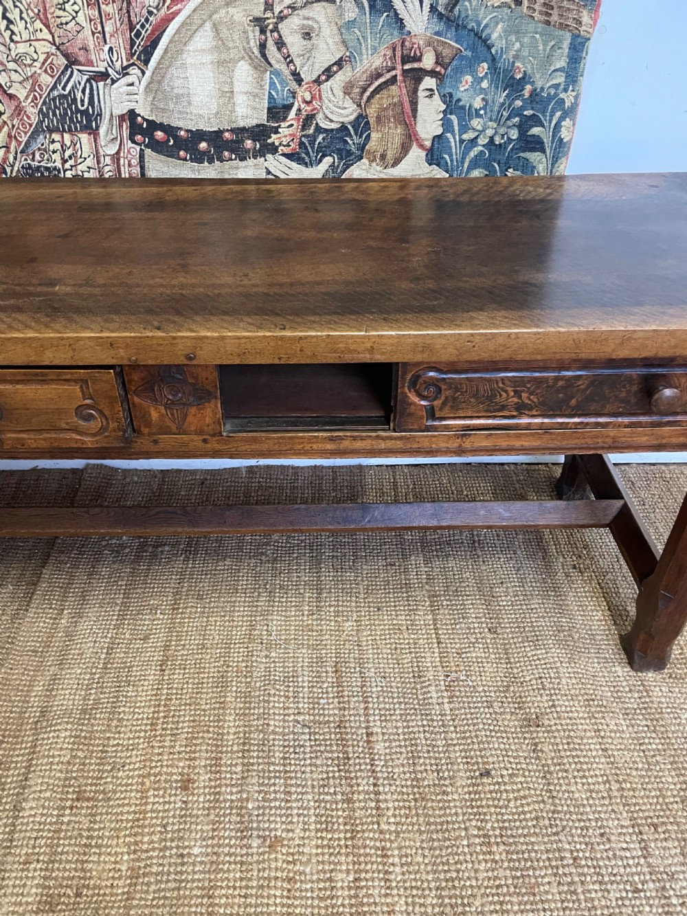 An elongated antique walnut console table featuring three drawers with brass hardware and low stretcher supports. View X