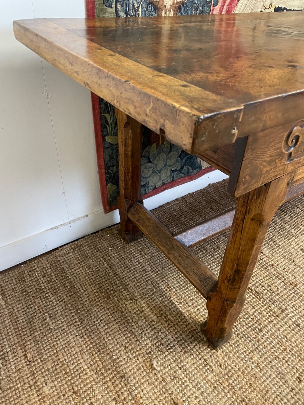 An elongated antique walnut console table featuring three drawers with brass hardware and low stretcher supports. View XV