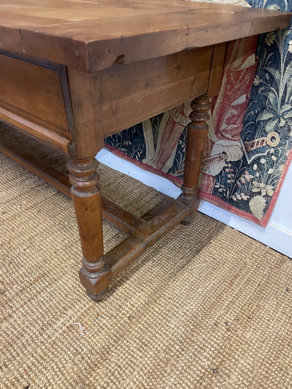 A long rectangular antique cherrywood console table featuring three frieze drawers with small brass knobs and turned legs connected by a low stretcher. View V