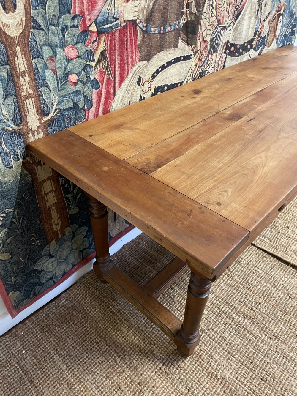 A long rectangular antique cherrywood console table featuring three frieze drawers with small brass knobs and turned legs connected by a low stretcher. View X
