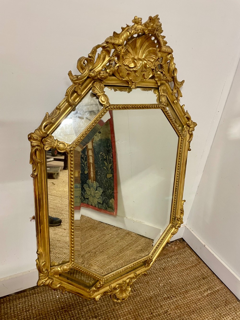 An ornate Napoleon III gilt cushion framed wall mirror with bevelled glass and carved scrollwork details.
