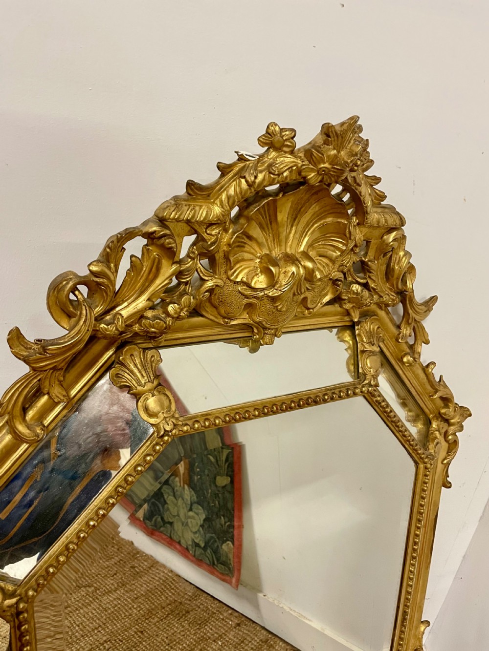 An ornate Napoleon III gilt cushion framed wall mirror with bevelled glass and carved scrollwork details. View II
