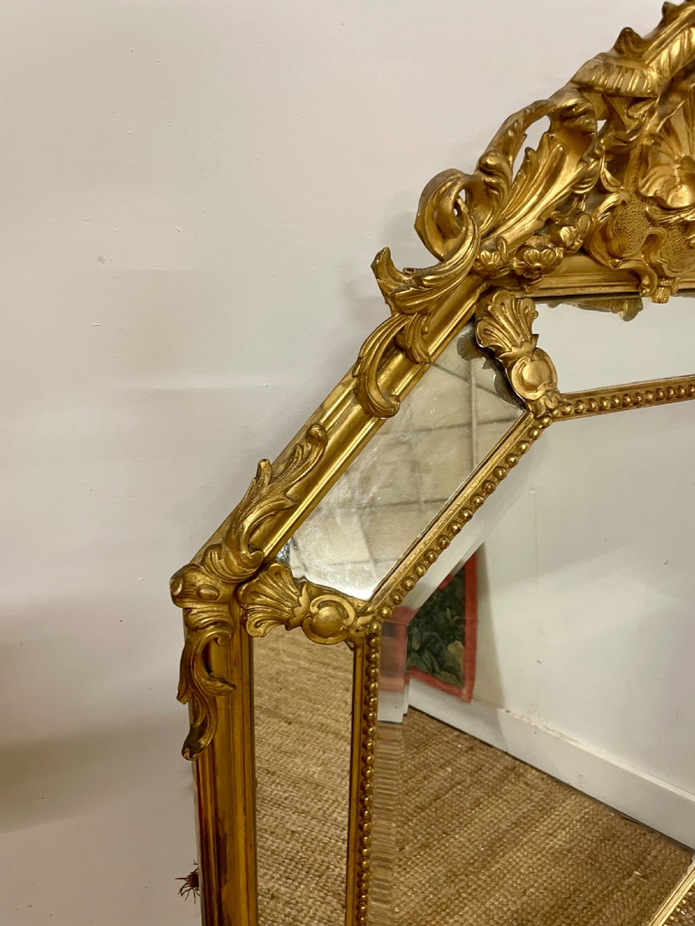 An ornate Napoleon III gilt cushion framed wall mirror with bevelled glass and carved scrollwork details. View III