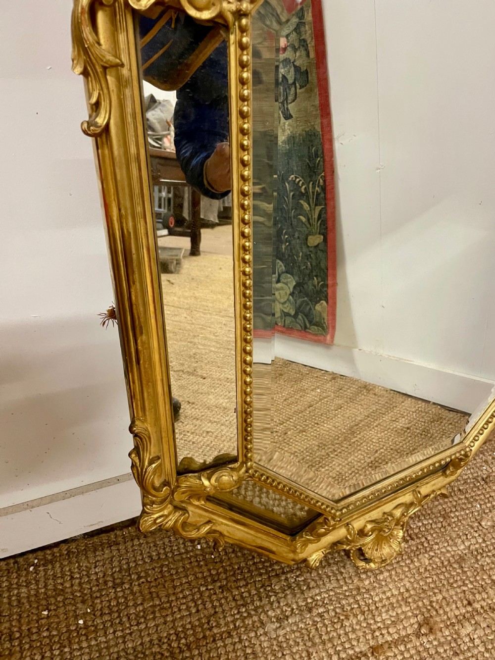 An ornate Napoleon III gilt cushion framed wall mirror with bevelled glass and carved scrollwork details. View IV